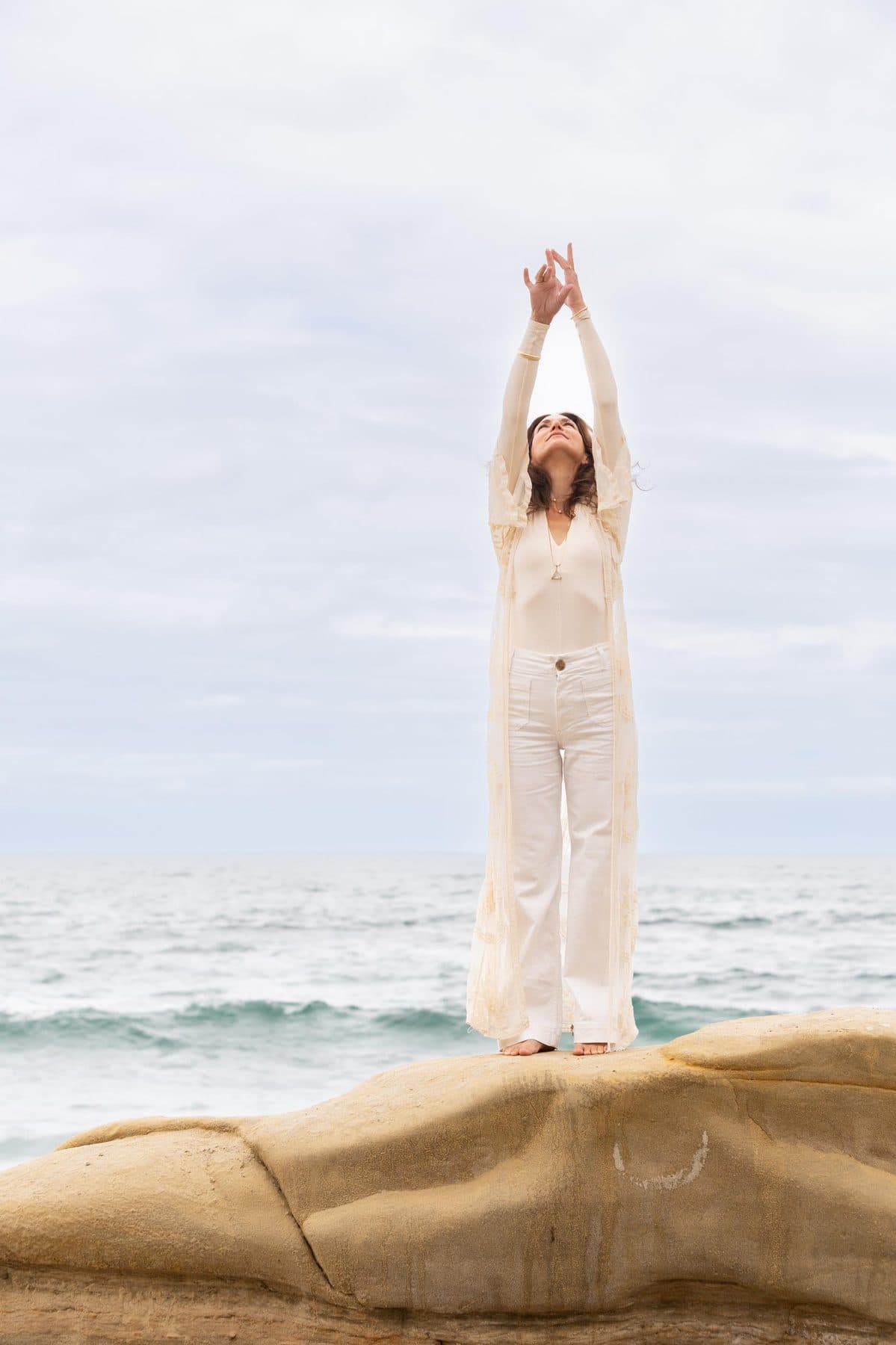 Standing on the rocks with arms raised to the sky